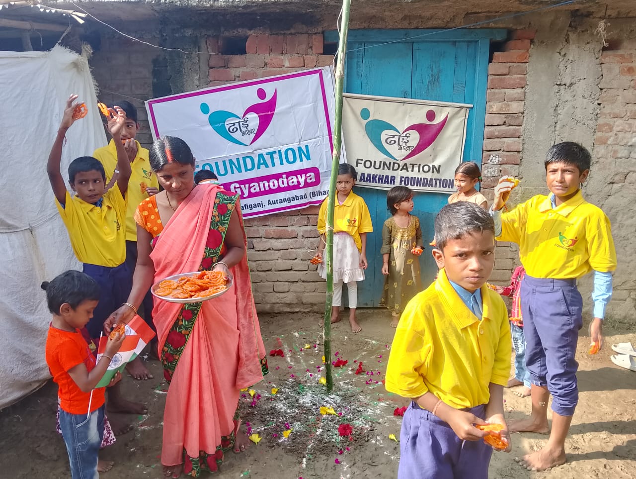 Children celebrating Independence Day at Dhai Aakhar Foundation with flags and sweets.